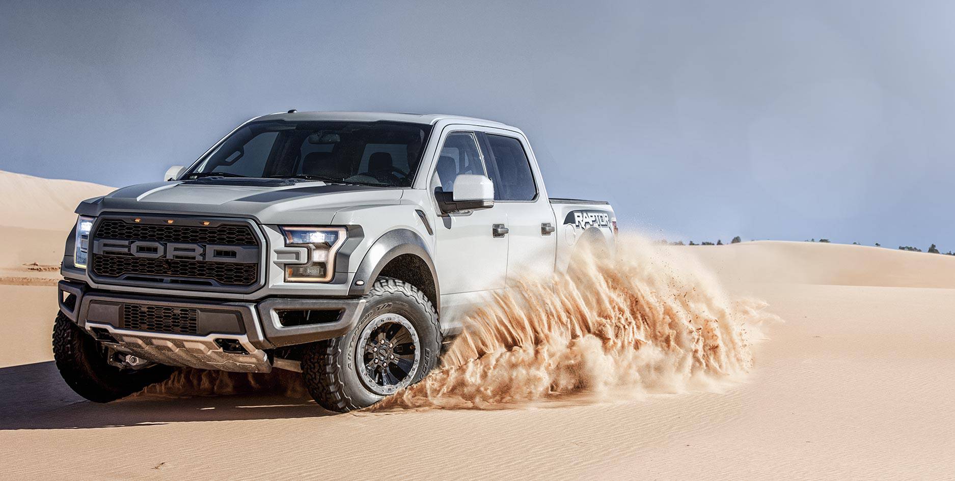 A white Ford F-150 truck driving through the desert.