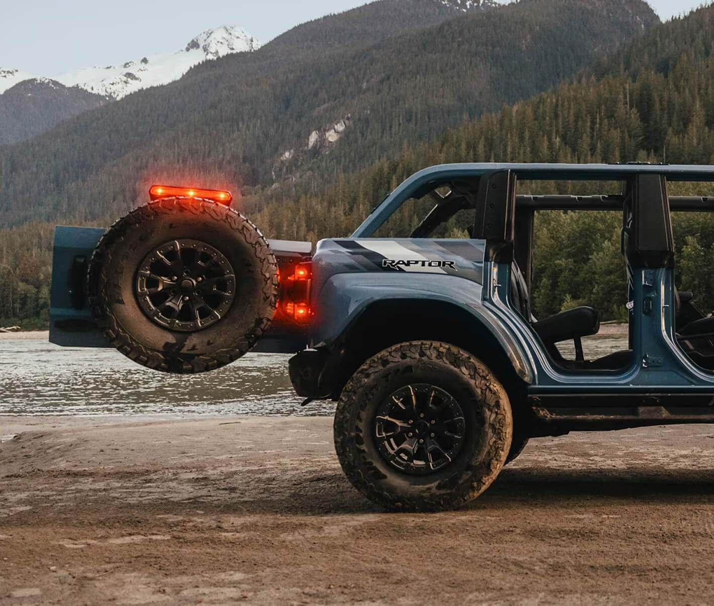 Ford Bronco Raptor off-road vehicle with LED light bar and spare tire in mountainous terrain